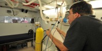 Todd Olin, a pulmonary fellow in Robert Roach’s lab, works the cycle ergometer in the hypobaric chamber while breathing a special gas mixture that is high in CO2. Roach wants to test Olin’s ability to hold CO2 levels constant.  Courtesy of Robert Roach