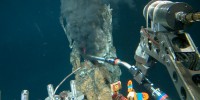 A mechanical arm on the Alvin submersible reaches out to take a sample from a 